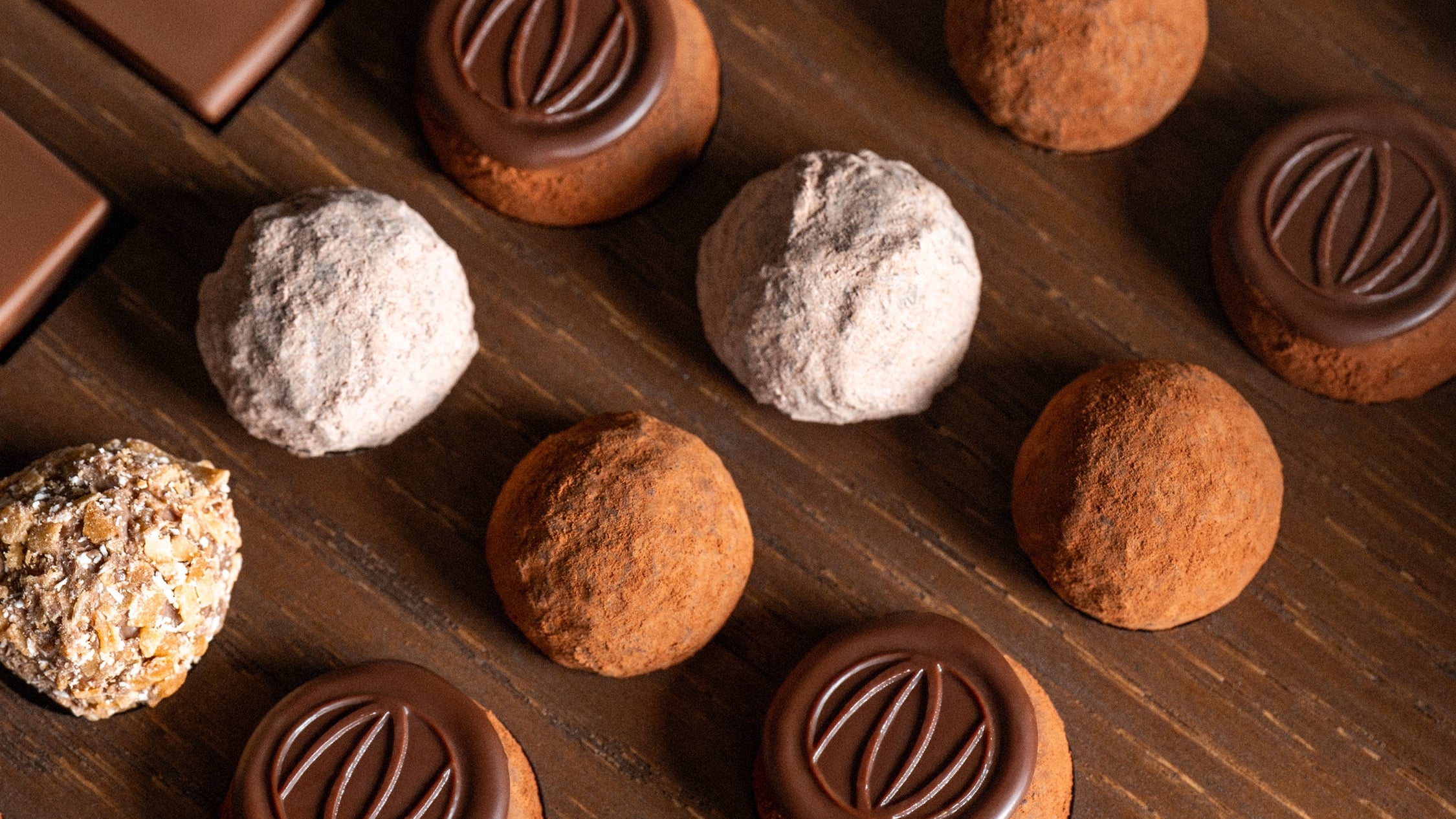 Assorted chocolates including bars and truffles on a wooden surface