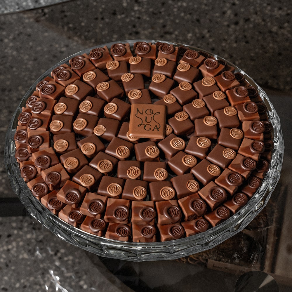 Glass classic bowl filled with chocolate candies featuring a visible brand logo.