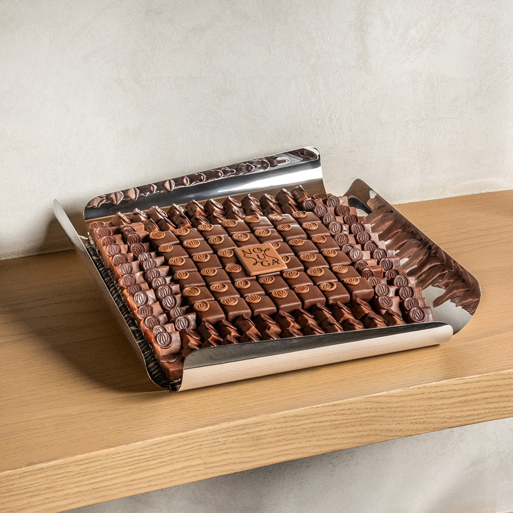 Chocolate bonbons sitting in the silver lustra tray on a surface with a neutral background