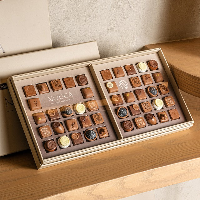 Open box of nouga chocolates on a wooden surface