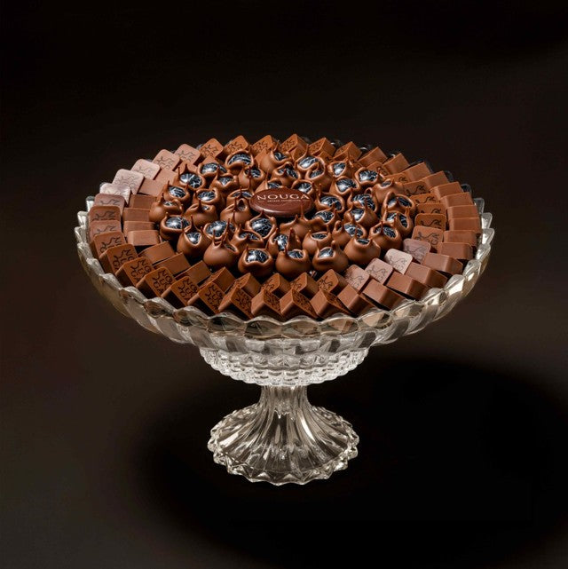 Decorative glass dish with chocolate candies on a dark background