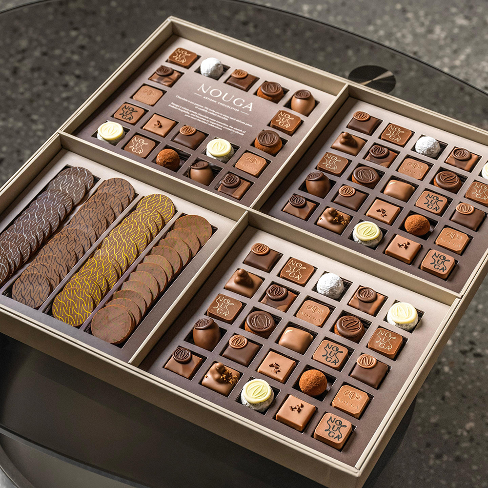 Assorted chocolate assortment in a decorative box on a dark glass surface