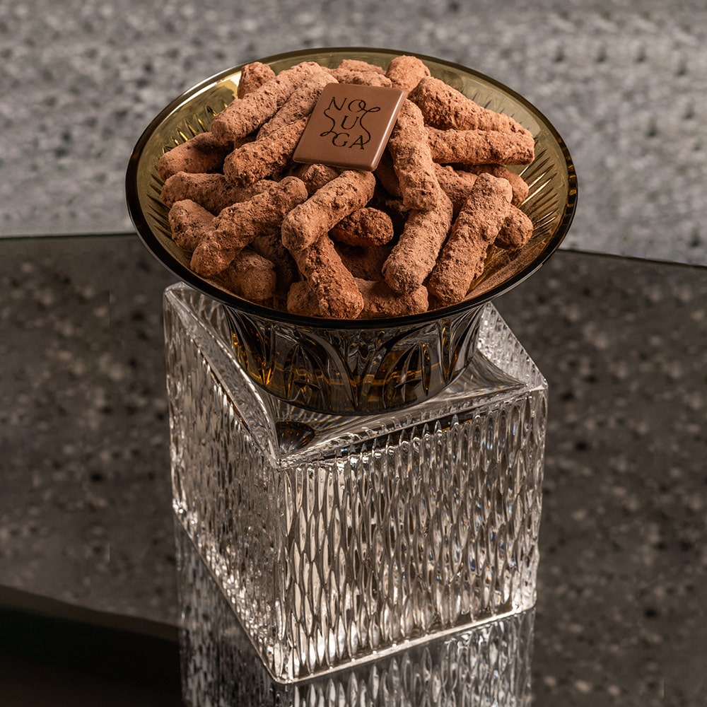 Decorative crystal bowl tray with chocolate treats on a glass table