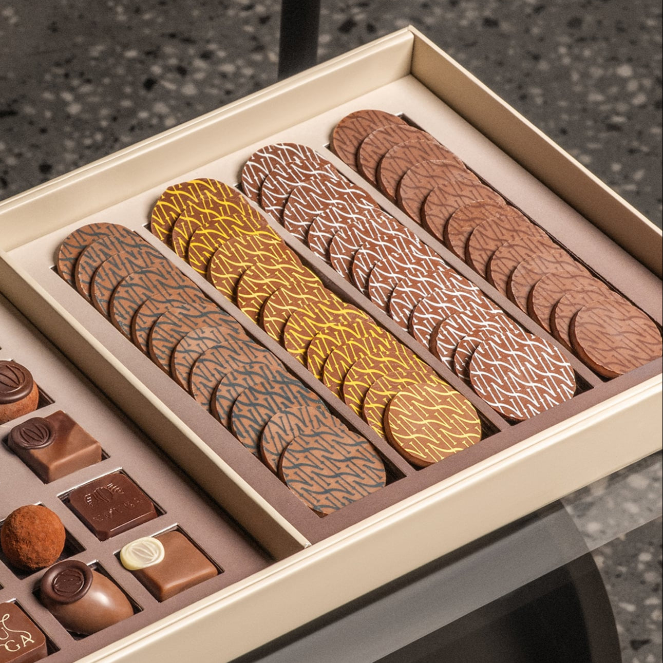 Assorted chocolates in a box on a textured surface