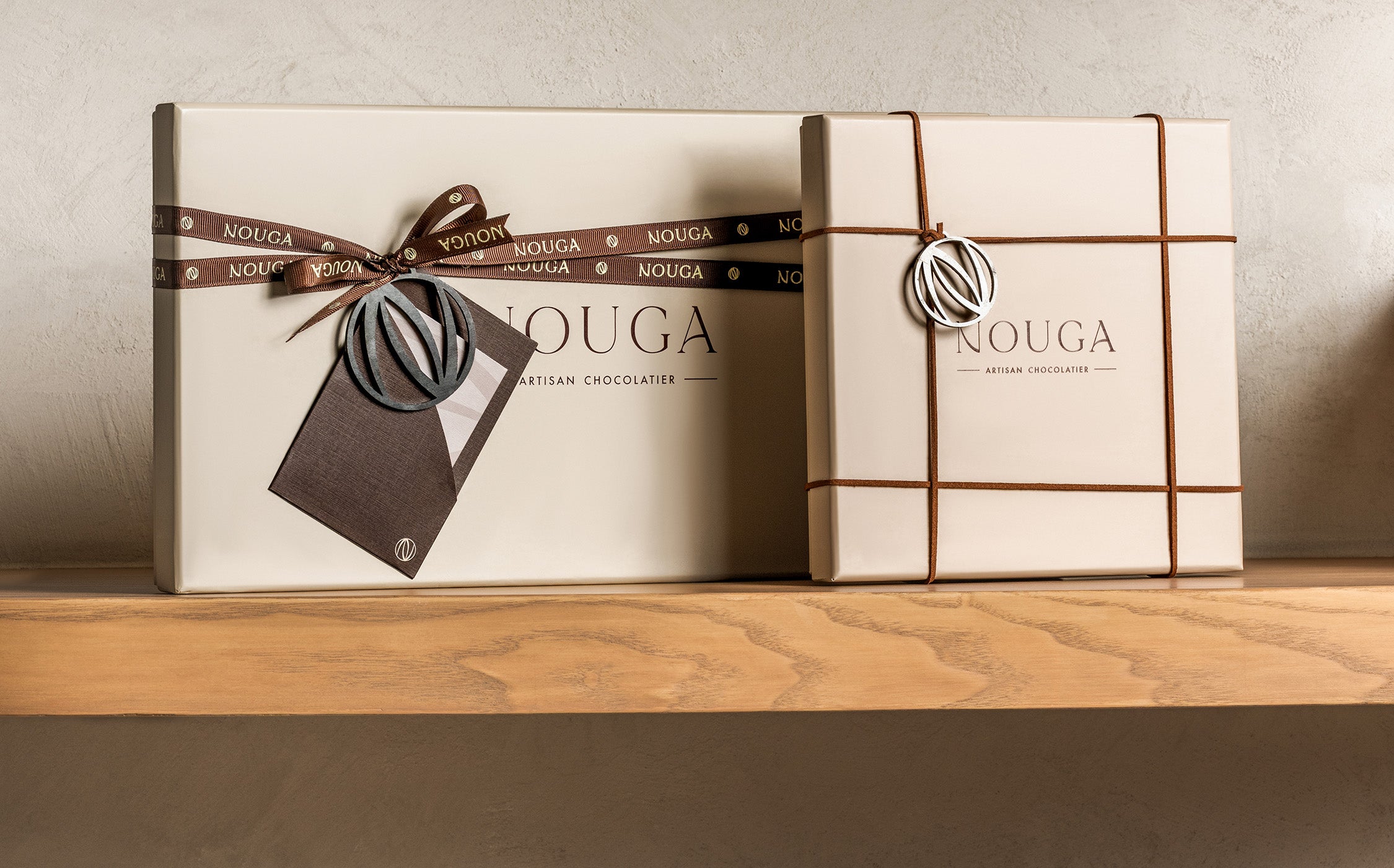 Two wrapped chocolate boxes with 'Nouga' branding on a wooden surface.
