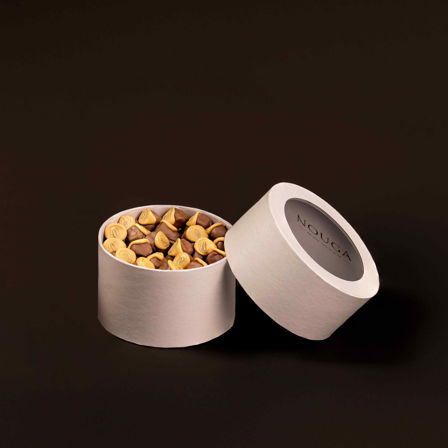 Open beige container with caramel wafer chocolate on a brown background, featuring the brand 'NOUGA'.