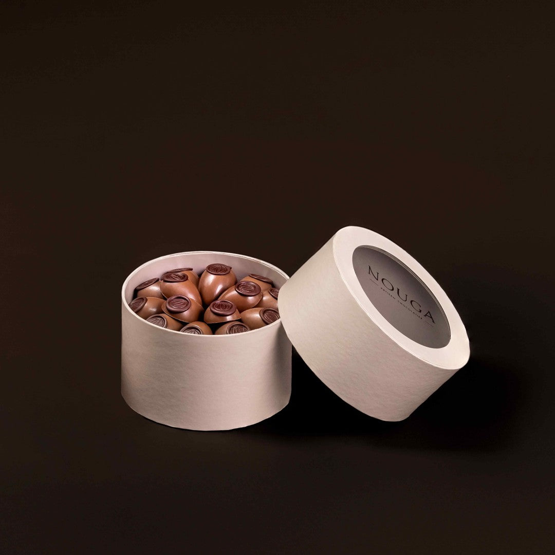 Open beige box filled with chocolate truffles on a dark background