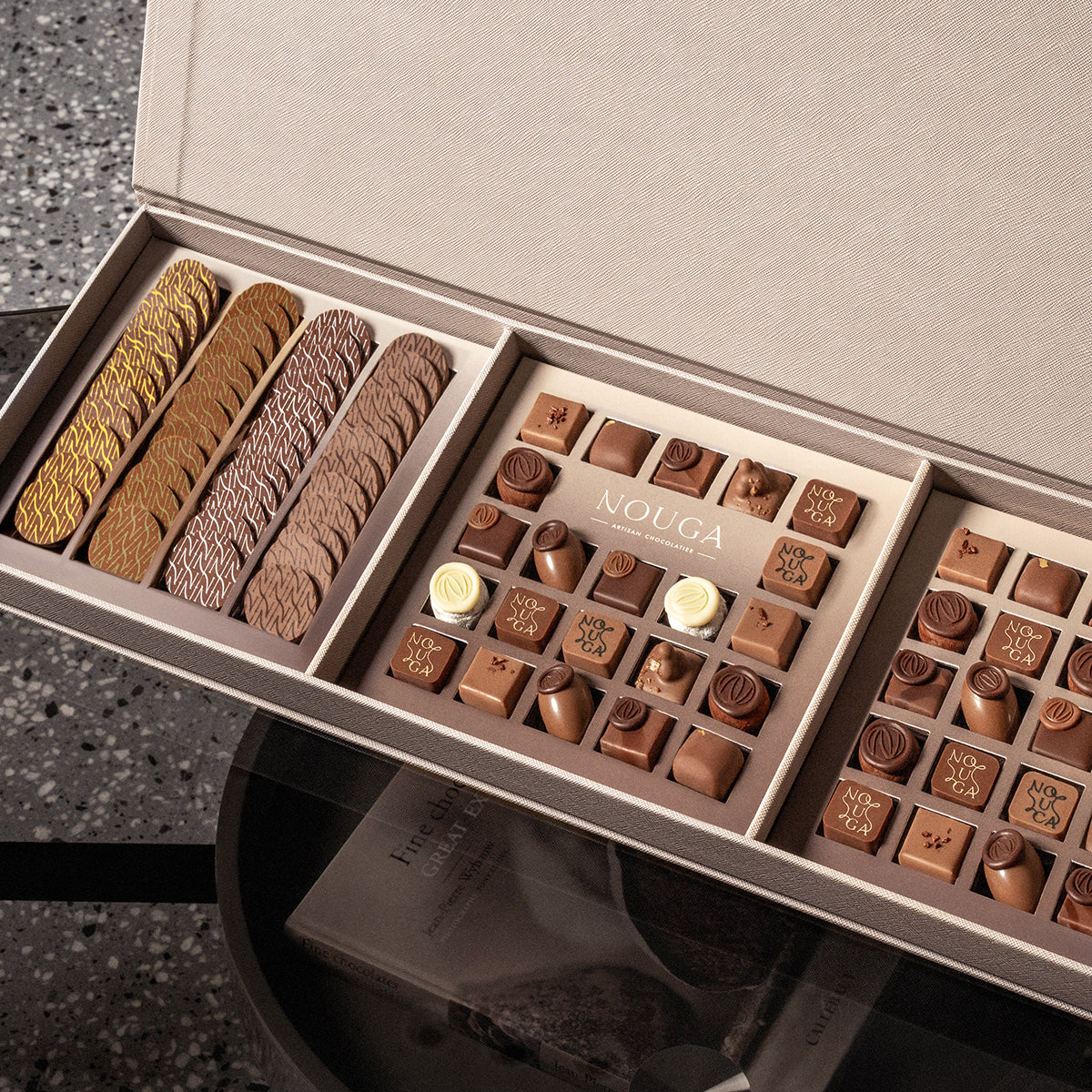 Premium chocolate arranged in a leather chocolate box placed on dark glass table