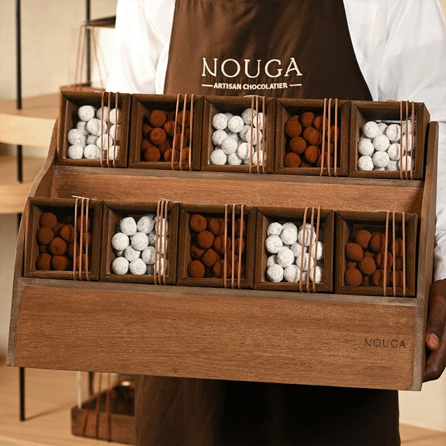 Wooden display of truffles held by person with a 'Nouga' apron