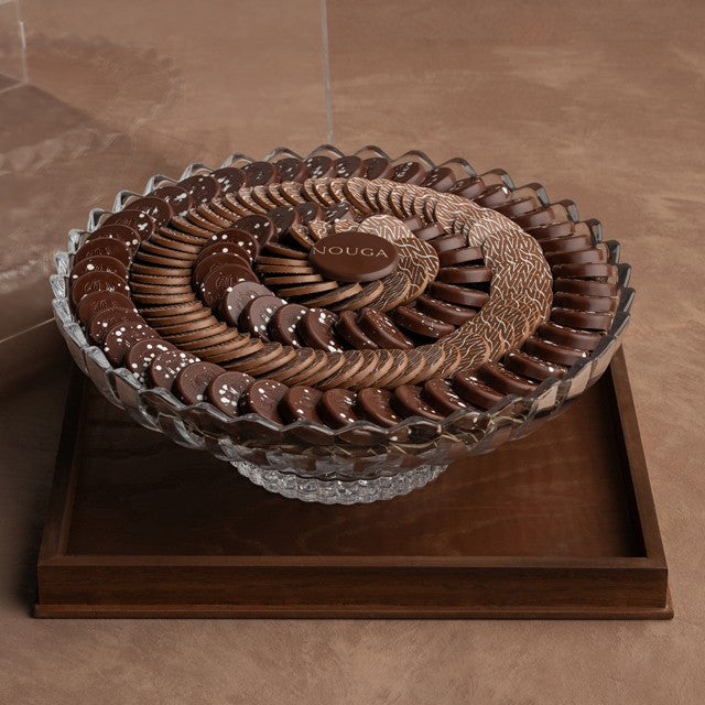 Decorative chocolate display with 'Nouga' branding on a wooden tray base and clear cover beside.