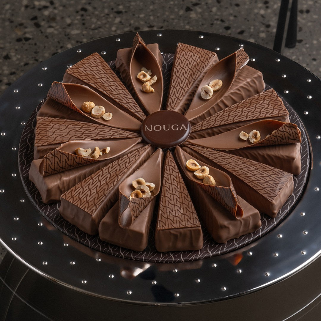 Chocolate cake with 'NOUGA' branding on a dark surface