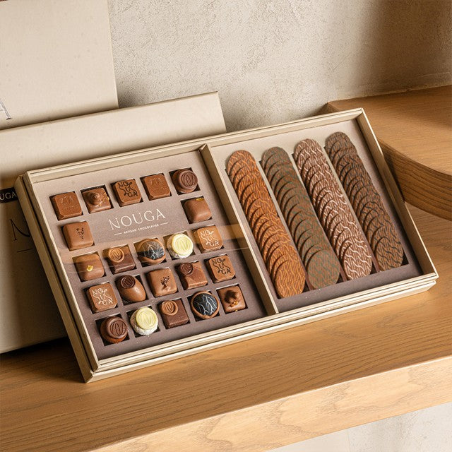 Open box of chocolates with various types on a wooden surface